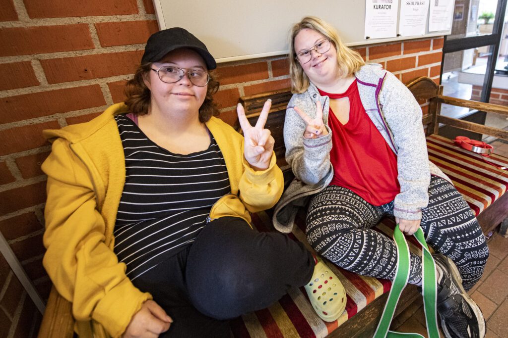 Två elever visar peacetecknet